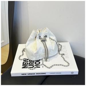Détail de la broderie papillon et du cordon perlé sur le sac seau blanc chic