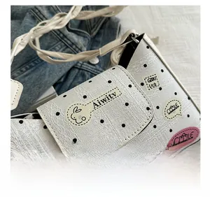 Close-up of white crossbody bag with black polka dots and cartoon texture details