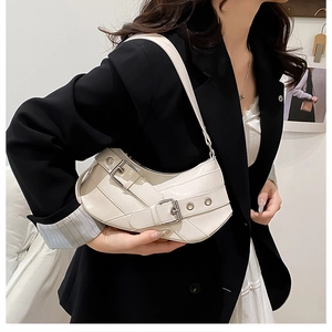 Detail of white glossy baguette bag with silver buckles on a black blazer model