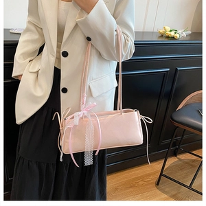 Détail d'un sac à bandoulière rose avec des rubans roses et des nœuds en dentelle blanche