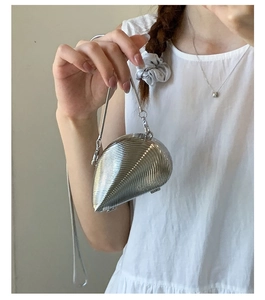 Detail of a silver metallic shell-shaped mini bag with fine ridges and snake chain
