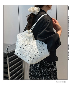 Close-up of a white tote bag featuring large lace bows, pearl charms, and tiny bow prints