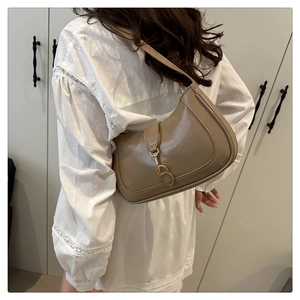 Detailed side view of khaki leather hobo bag with decorative metal clasp and strap