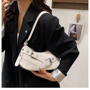 Macro detail of creamy white PU leather underarm bag with silver buckles and grommets
