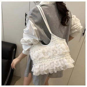 Detailed side view of a white lace shoulder bag with tiered ruffles and minimalist straps
