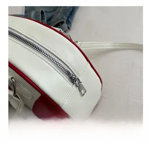 Detail van zilveren rits op rood-witte lederen bowlingtas met strak stiksel