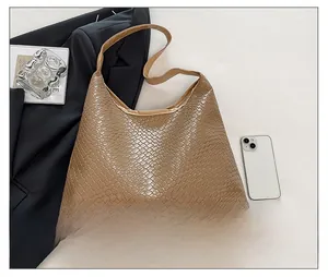 Top view of brown woven texture tote bag with matching strap on a black blazer backdrop