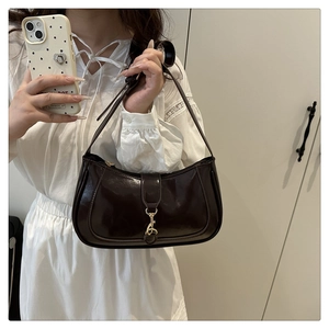 Detail of dark brown glossy patent leather hobo bag with elegant gold metal buckle