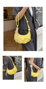 Detail of yellow pleated half-moon shoulder bag with rope strap and pink charm