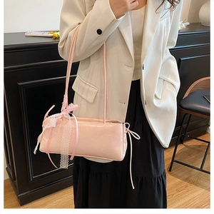Détail du sac à bandoulière rose clair avec nœud en dentelle blanche et rubans élégants