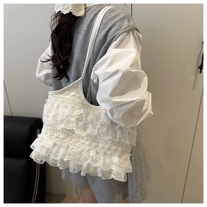 Detailed view of white lace ruffles and mesh fabric on a tiered tote shoulder bag