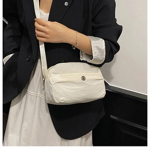 Close-up of minimalist nylon crossbody bag with textured fabric and metal logo detail