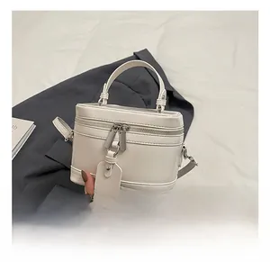 Detail showing the white leather mini crossbody bag with silver zippers and top handle