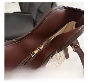 Detailed close-up of smooth gold zipper and brown leather trim on woven tote bag