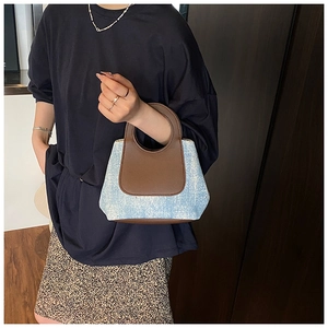 Dettaglio della borsa a secchiello in denim blu e pelle marrone a contrasto