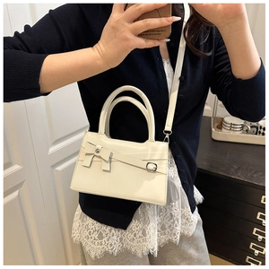 Détail d'un sac à main blanc crème avec un nœud décoratif et des poignées élégantes