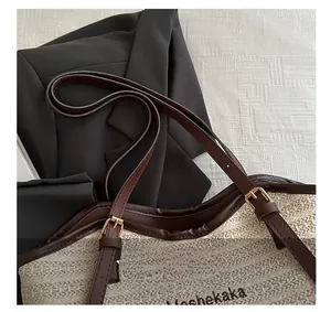 Detail of woven tote bag featuring brown leather handle and gold metal adjustable buckle