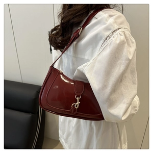 Detail of burgundy glossy patent leather shoulder bag with gold metal lobster clasp