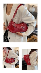 Macro detail of red patent leather crescent bag with decorative metallic eyelets and buckle