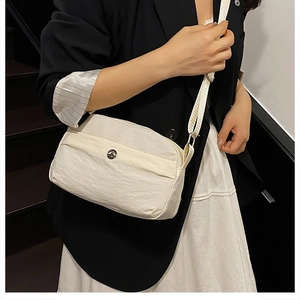 Detail view of cream nylon crossbody bag with adjustable strap on professional model