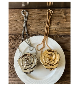 Detail of rose-shaped gold and silver acrylic mini bags on a white plate with metal chains