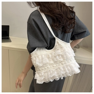 Detail of white lace tote bag with tiered ruffle design and long shoulder strap
