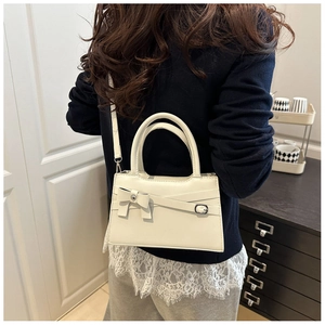 Détail du sac à bandoulière en similicuir blanc cassé avec ceinture et nœud élégant