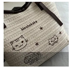 Detail view of straw woven bag with leather trim and cute animal embroidery accents