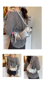 Detail of silver metallic pleated cloud bag featuring heart charm and braided pendant decor