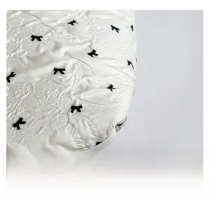 Detail of white tote bag fabric featuring pleated texture and black bow print patterns