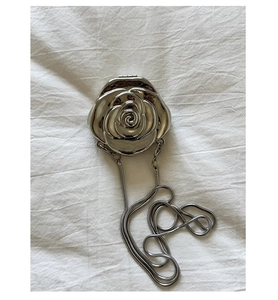 Macro shot of silver metallic rose evening bag featuring 3D floral petals and chain