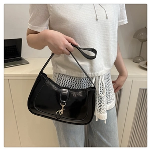 Detail of glossy black hobo bag featuring a gold metal lobster clasp and premium finish