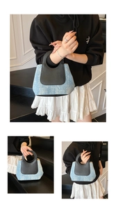 Detail of blue denim and black leather contrast stitching on a stylish tote handbag