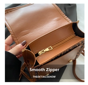 Close-up of smooth metal zipper and magnetic buckle on leopard print crossbody bag