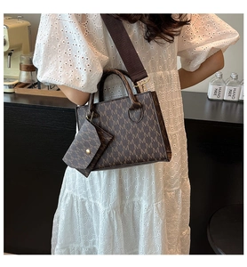 Detail of a brown square tote bag with M-pattern monogram and detachable wide strap