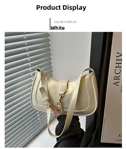 Detail of a minimalist cream white shoulder bag with a gold piston clasp and adjustable strap