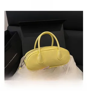 Detail shot of yellow patent leather bowling bag with top handles and gold zipper