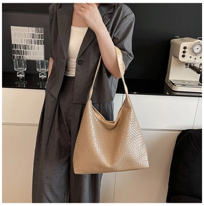 Close-up of beige leather woven tote bag showing Intrecciato craftsmanship in a modern cafe
