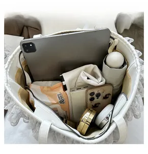 Vue intérieure du sac cabas en dentelle blanche montrant le rangement spacieux pour tablette