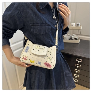 Close-up of white polka dot crossbody bag with colorful cat patches and thin strap