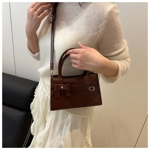 Détail d'un sac bandoulière marron élégant avec un nœud chic et une boucle métallique
