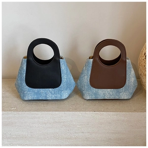 Detail view of denim bucket bags with smooth leather handles and trapezoid design