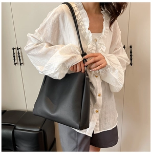 Model wearing a black leather tote bag in a minimalist indoor setting for summer style
