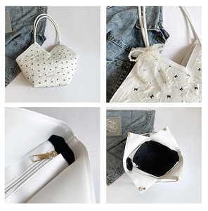Detail view of white tote bag with embossed bow patterns and pearl lace charm