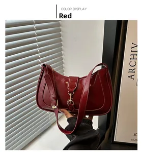 Detail of burgundy patent leather handbag with gold buckle and adjustable strap