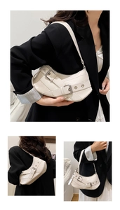 Close-up of ivory crescent underarm bag featuring parallel buckles and silver hardware