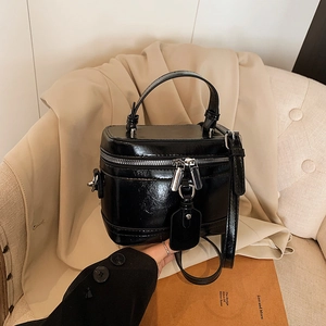 Luxurious black box handbag in glossy synthetic leather with adjustable shoulder strap