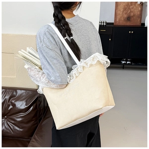 Détail du sac cabas en dentelle beige montrant sa grande capacité avec des livres