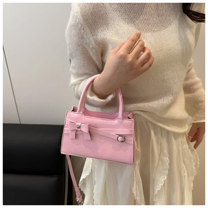Sac à main rose avec nœud décoratif et bandoulière porté par un mannequin