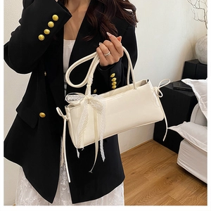 Gros plan d'un sac à bandoulière crème brillant avec ruban en dentelle et détails de cordon